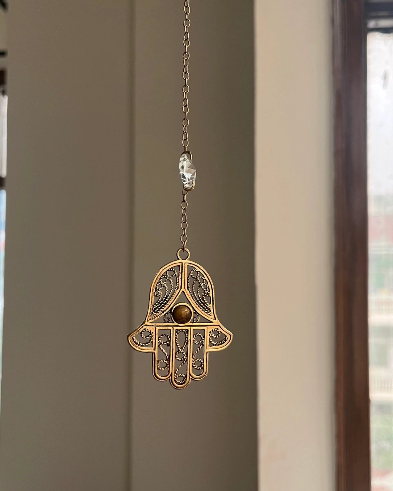 Brass hamsa-shaped car charm with a central gemstone handmade by A Creator's Studio
