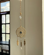 Brass dreamcatcher-shaped car charm with a central gemstone and feather hangings handmade by A Creator's Studio