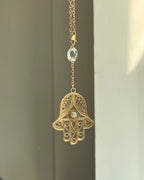 Brass hamsa-shaped car charm with a central gemstone handmade by A Creator's Studio
