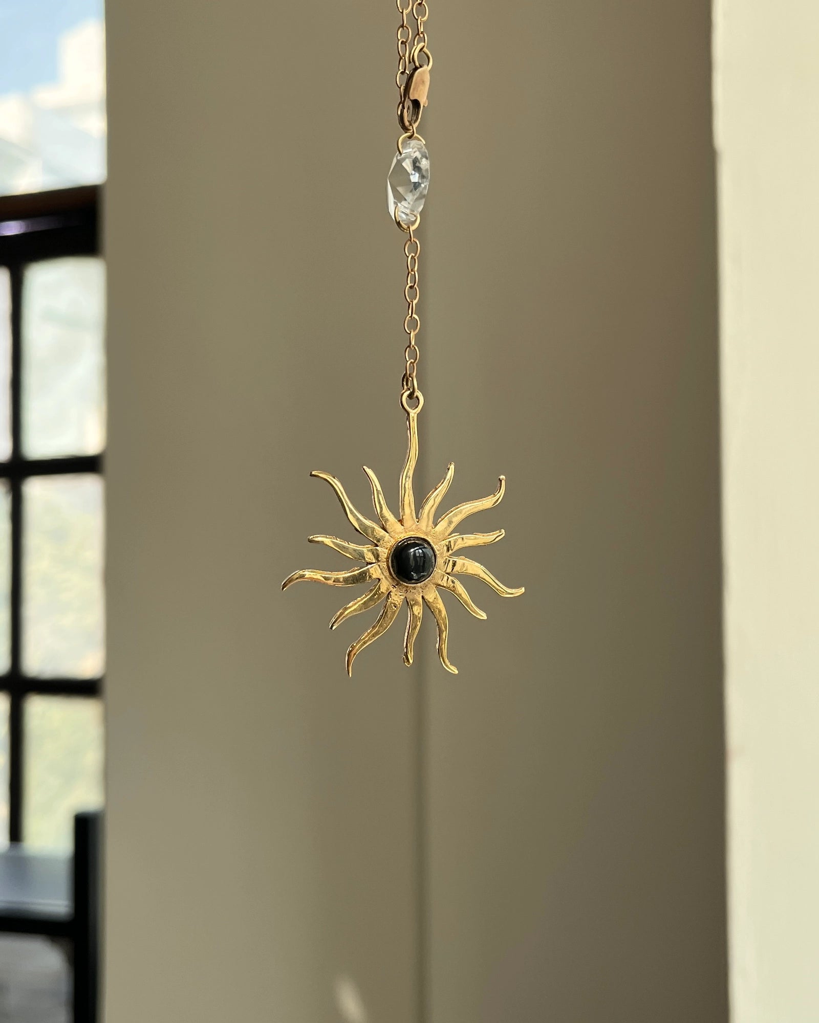 Brass sun-shaped car charm with a central gemstone handmade by A Creator's Studio