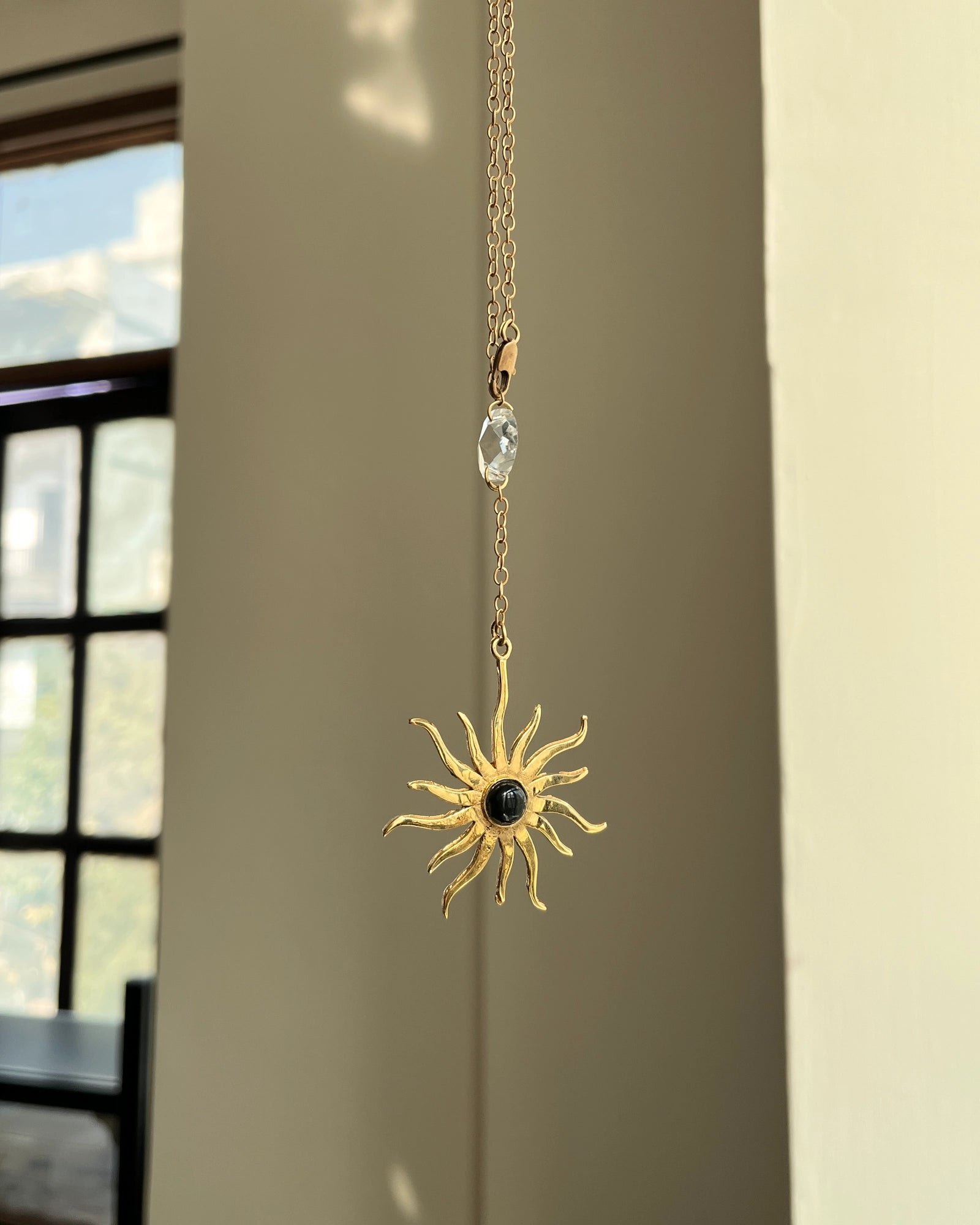 Brass sun-shaped car charm with a central gemstone handmade by A Creator's Studio