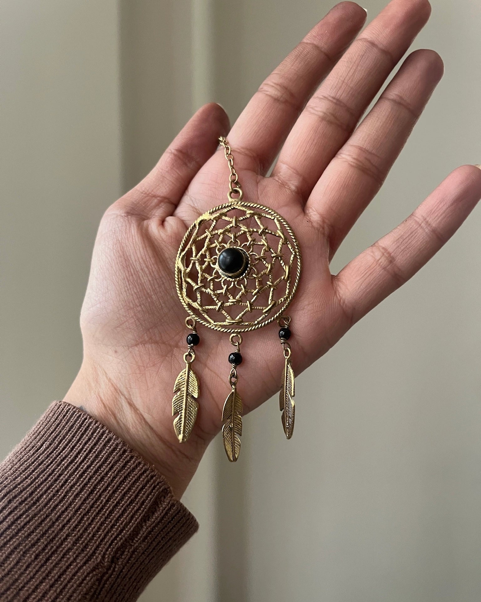 Brass dreamcatcher-shaped car charm with a central gemstone and feather hangings handmade by A Creator's Studio