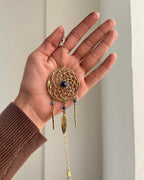Brass dreamcatcher-shaped car charm with a central gemstone and feather hangings handmade by A Creator's Studio