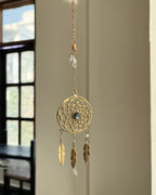 Brass dreamcatcher-shaped car charm with a central gemstone and feather hangings handmade by A Creator's Studio
