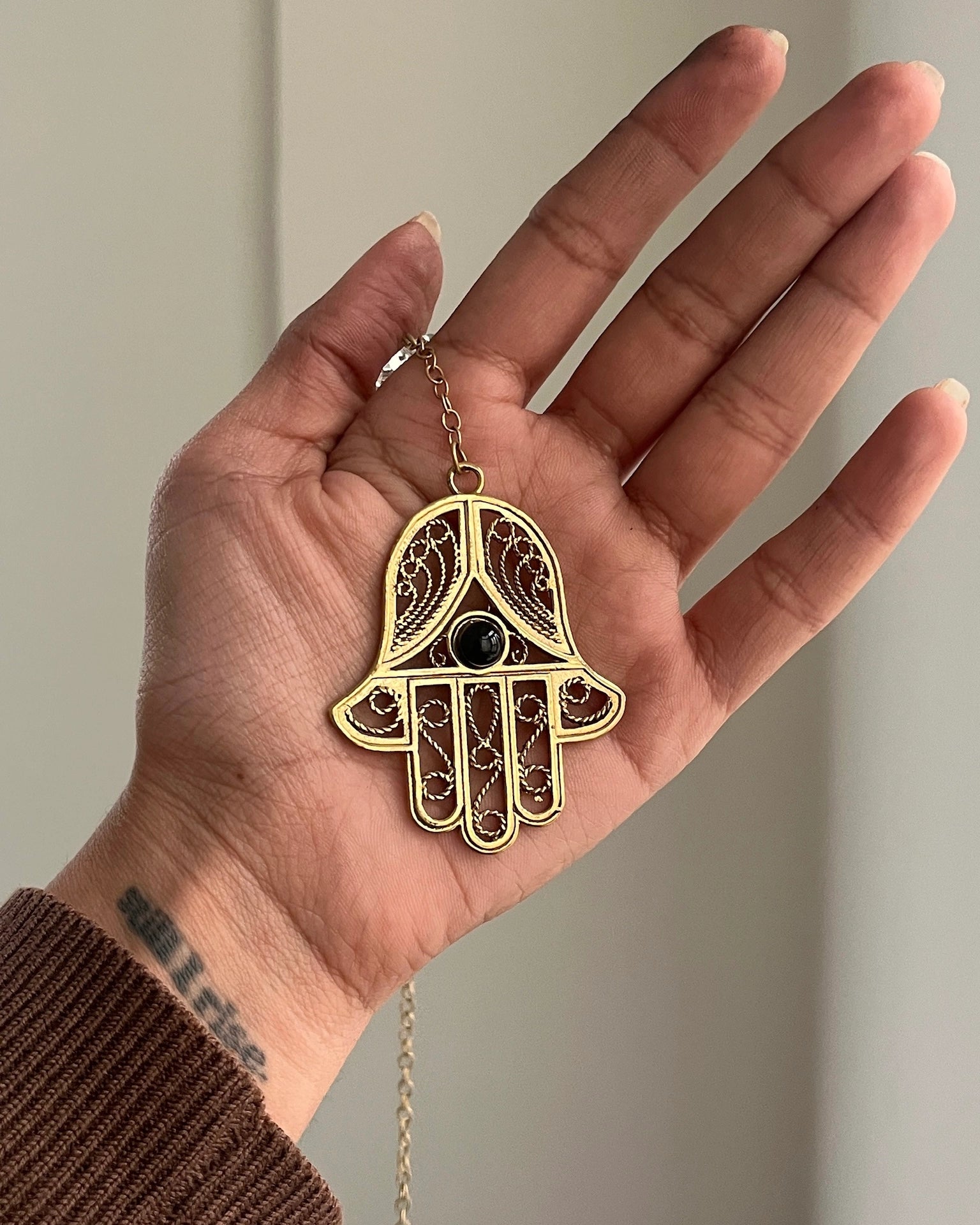 Brass hamsa-shaped car charm with a central gemstone handmade by A Creator's Studio