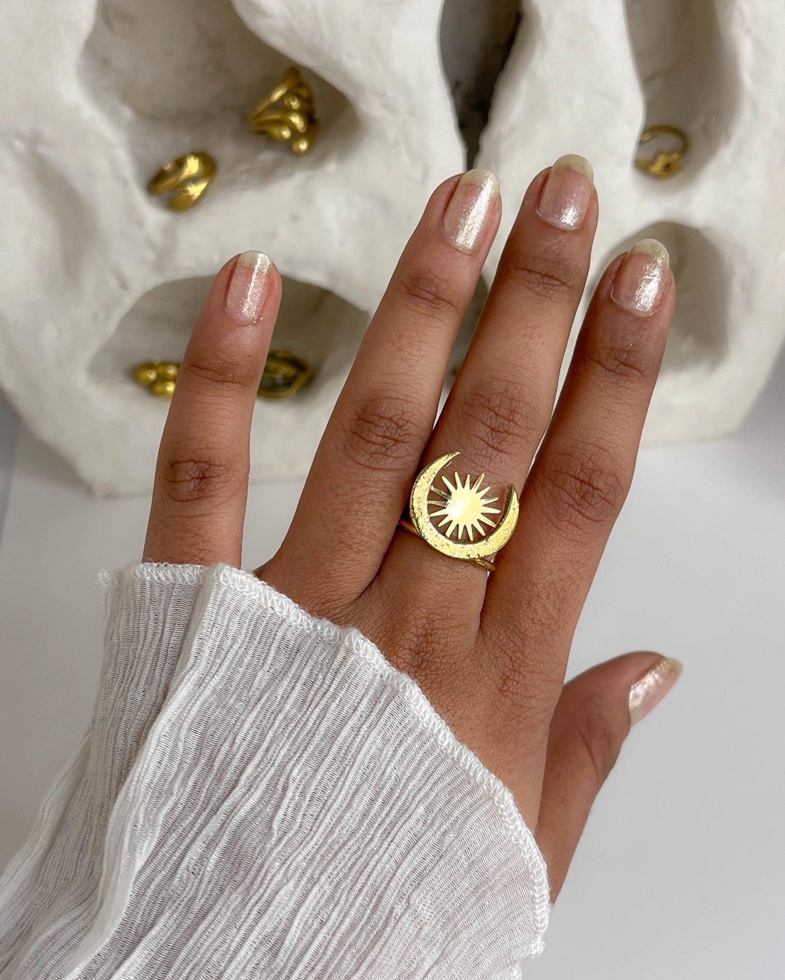 Hand wearing a brass ring with sun and moon design handmade by a creator's studio