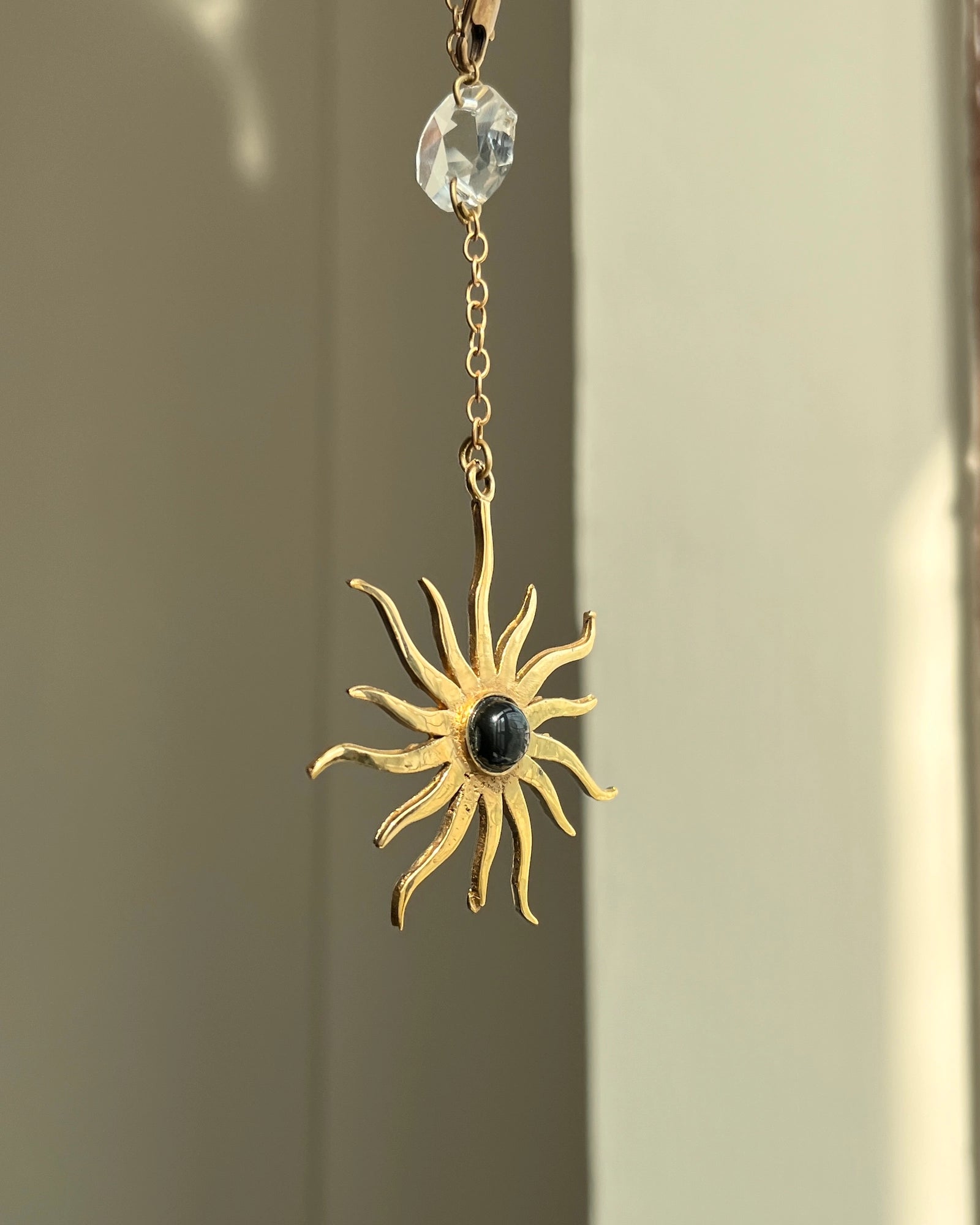 Brass sun-shaped car charm with a central gemstone handmade by A Creator's Studio