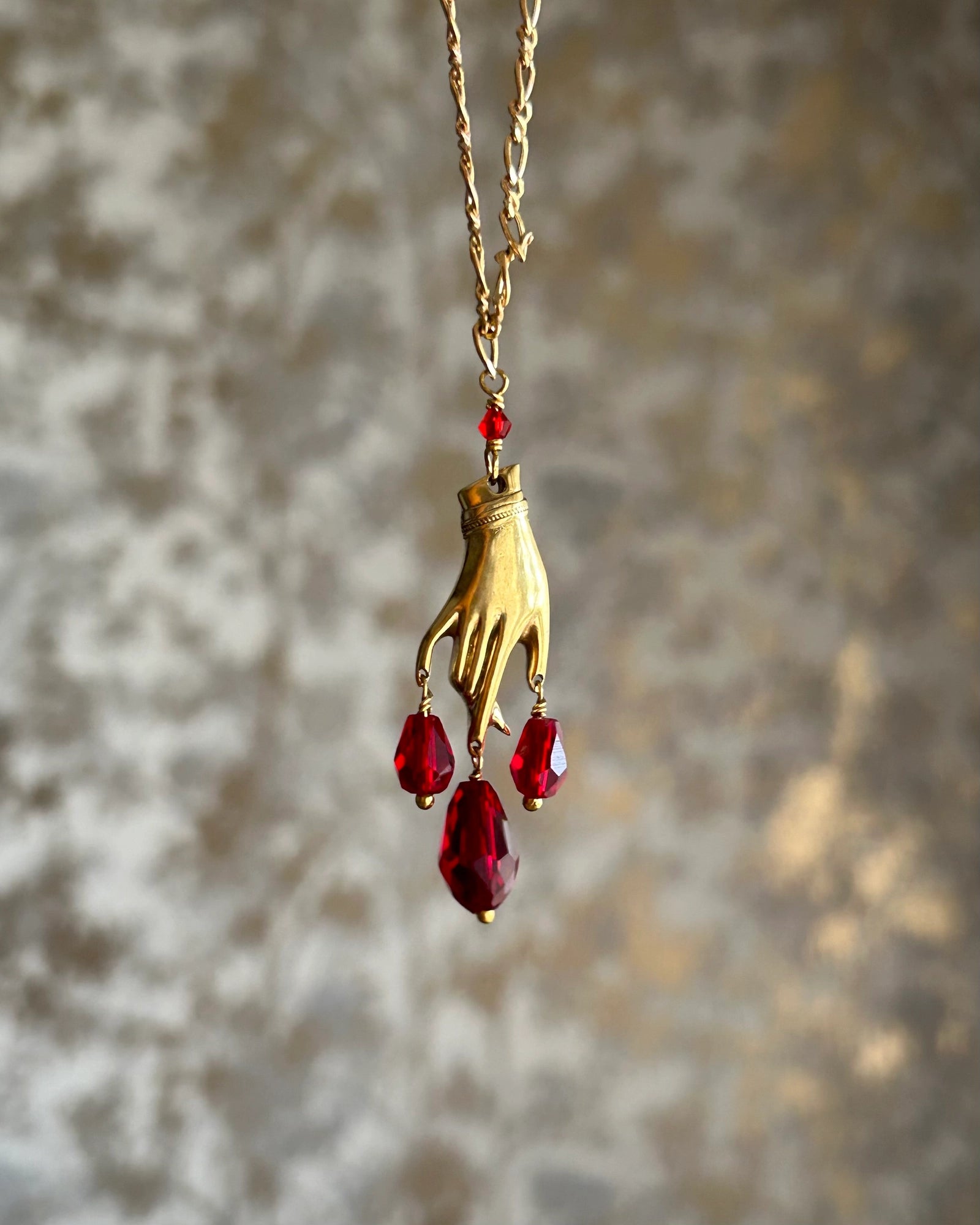 Brass necklace with a hand pendant and red crystal drops handmade by A Creator's Studio