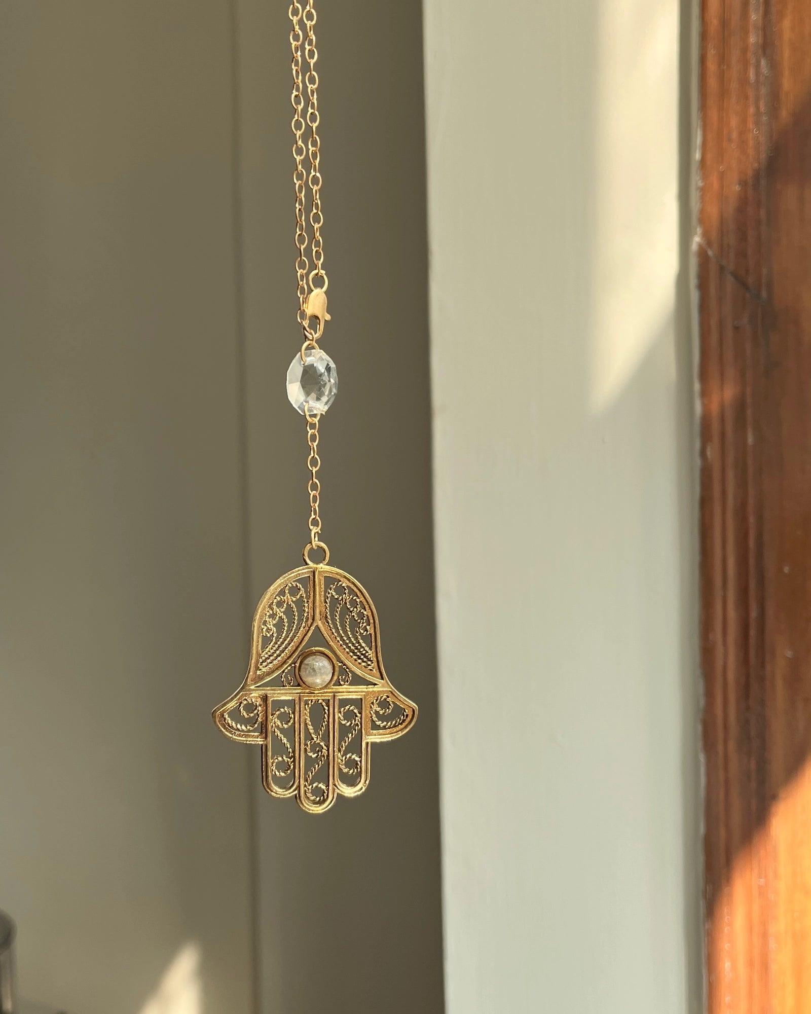 Brass hamsa-shaped car charm with a central gemstone handmade by A Creator's Studio