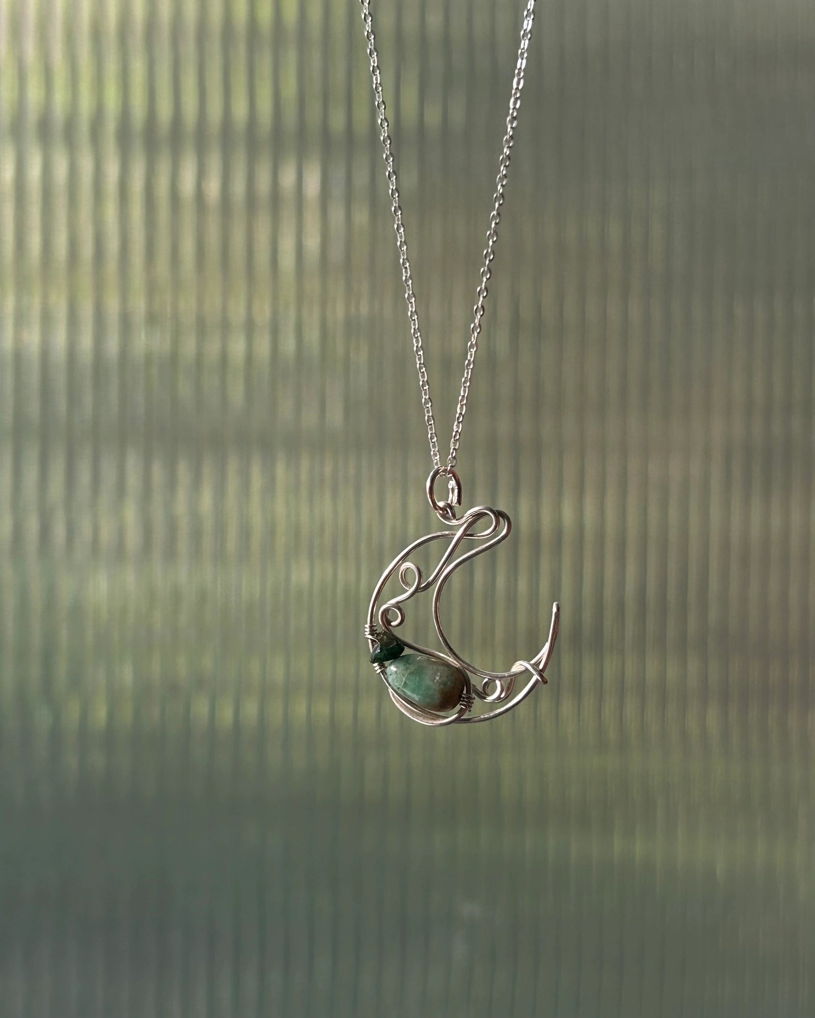 Sterling Silver Necklace with a wire wrapped moon pendant and an emerald gemstone handmade by A Creator's Studio