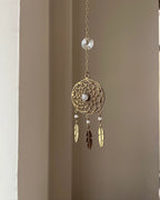 Brass dreamcatcher-shaped car charm with a central gemstone and feather hangings handmade by A Creator's Studio
