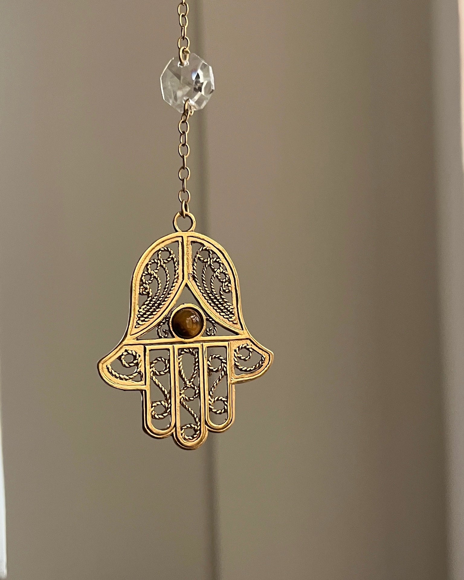 Brass hamsa-shaped car charm with a central gemstone handmade by A Creator's Studio