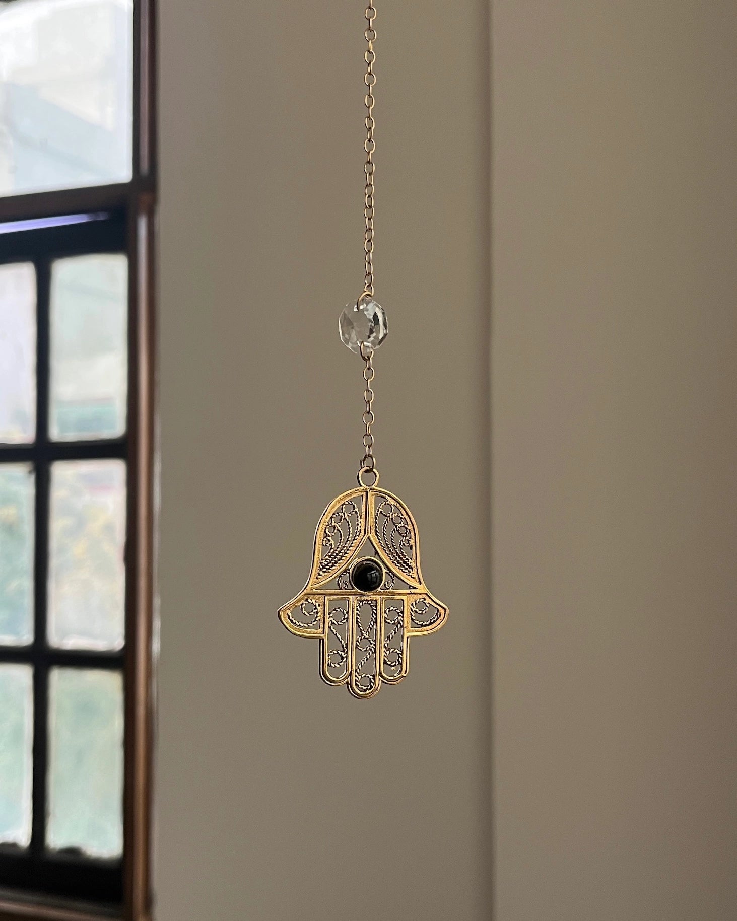 Brass hamsa-shaped car charm with a central gemstone handmade by A Creator's Studio