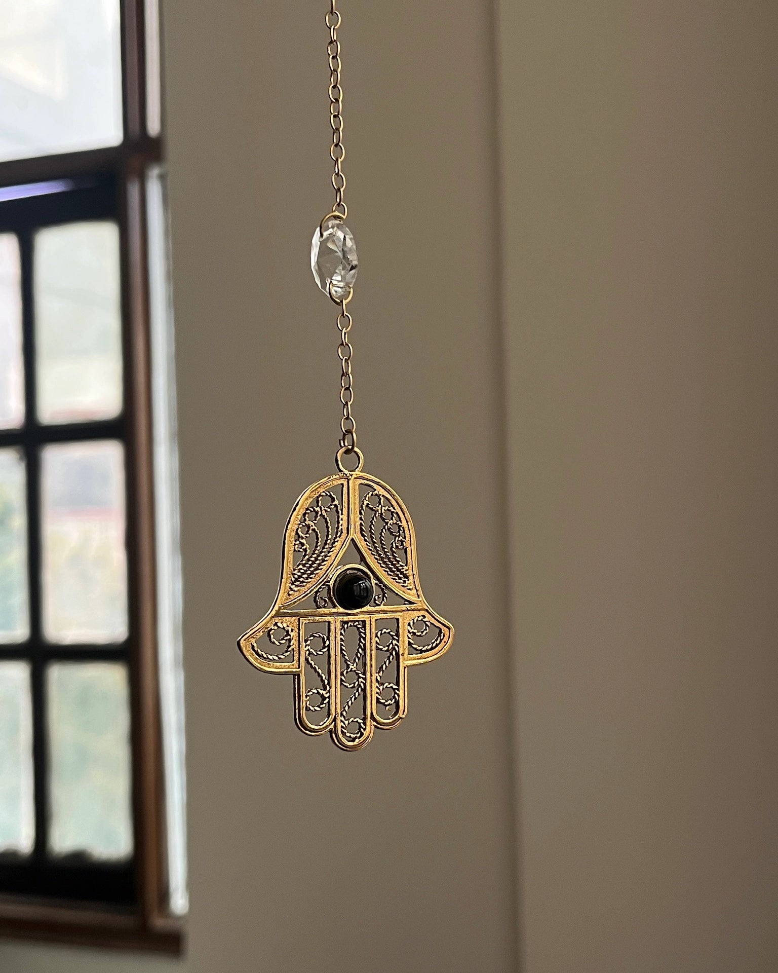 Brass hamsa-shaped car charm with a central gemstone handmade by A Creator's Studio