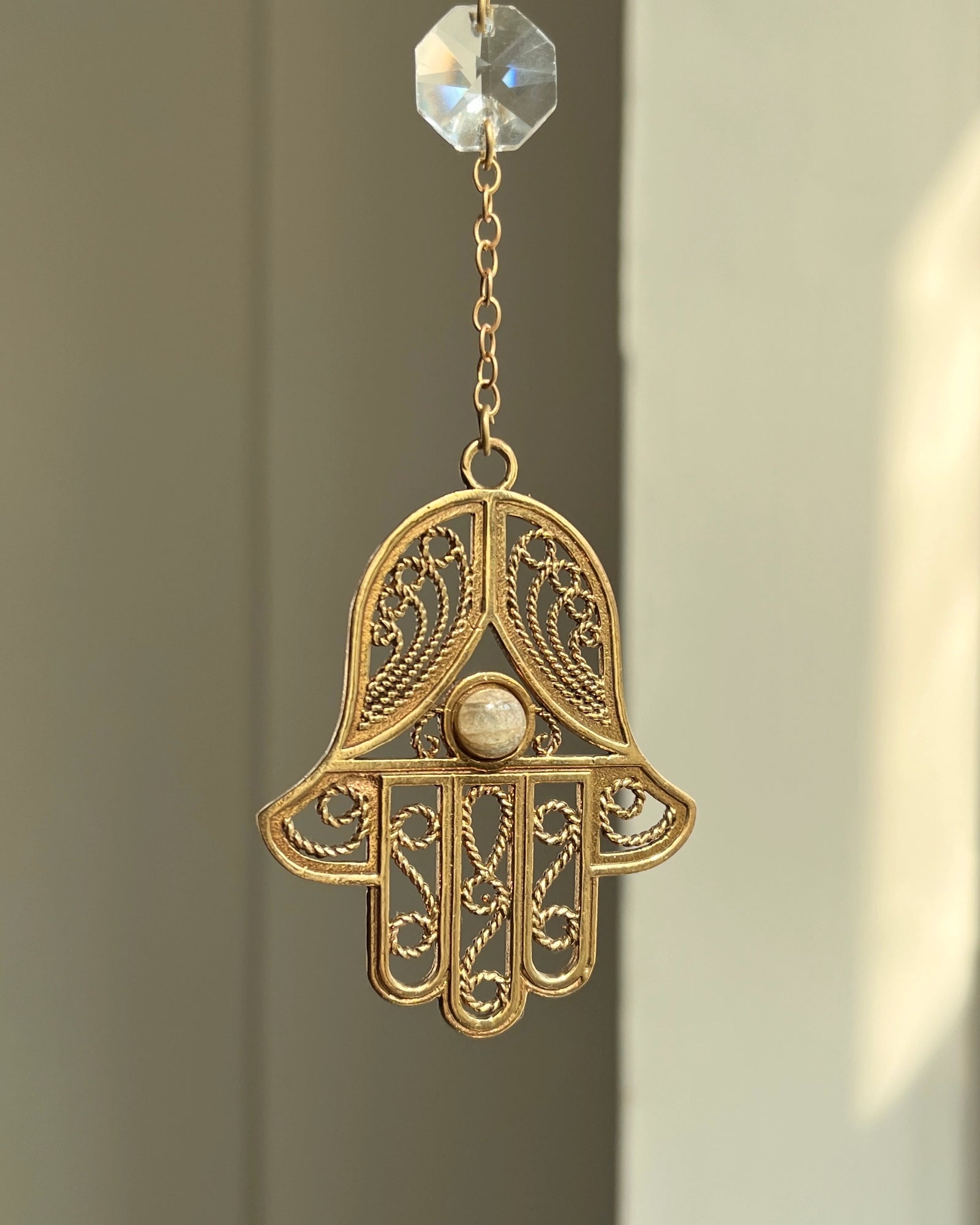 Brass hamsa-shaped car charm with a central gemstone handmade by A Creator's Studio